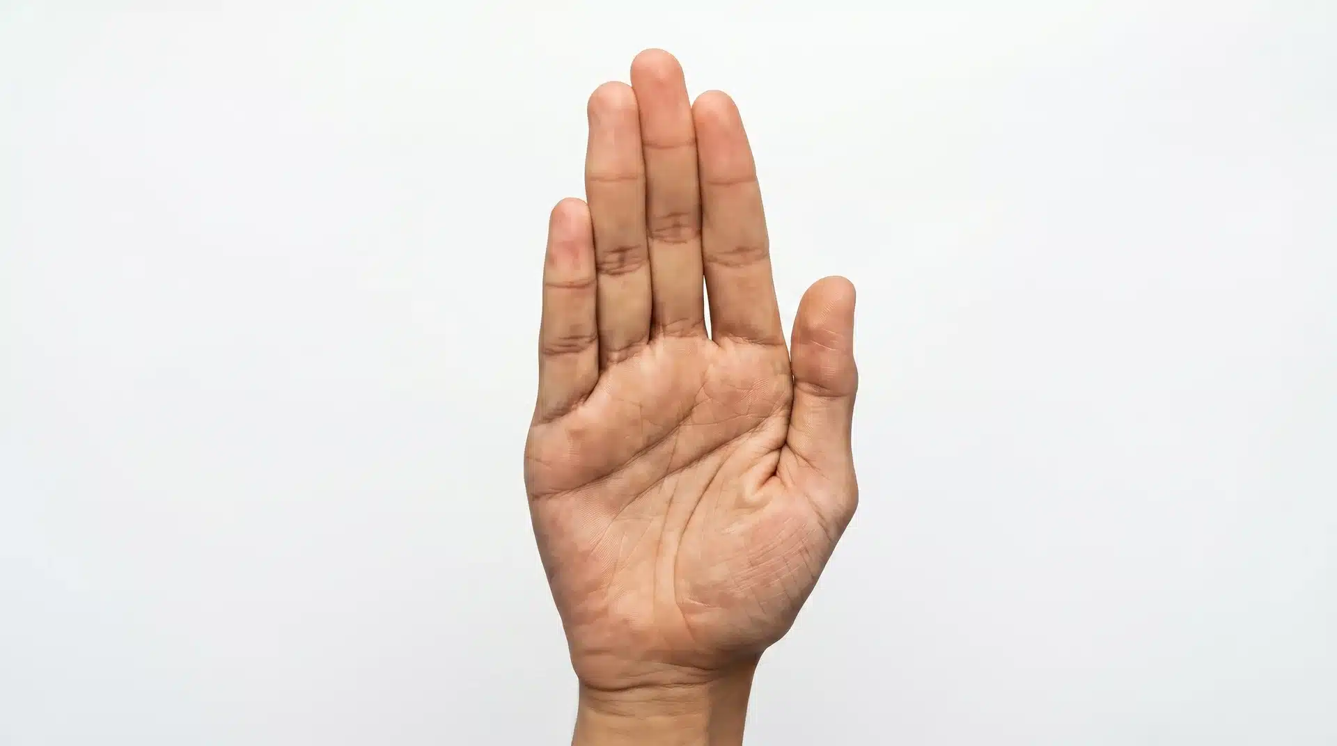Close-up of a person's hand raised to shoulder height with the palm facing outward and fingers pointing up in Abhaya Mudra.