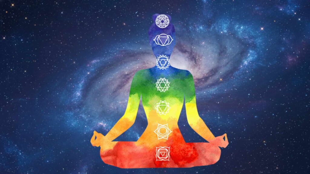Watercolor illustration of a person meditating in a yoga pose with seven glowing chakras against a starry galaxy background.