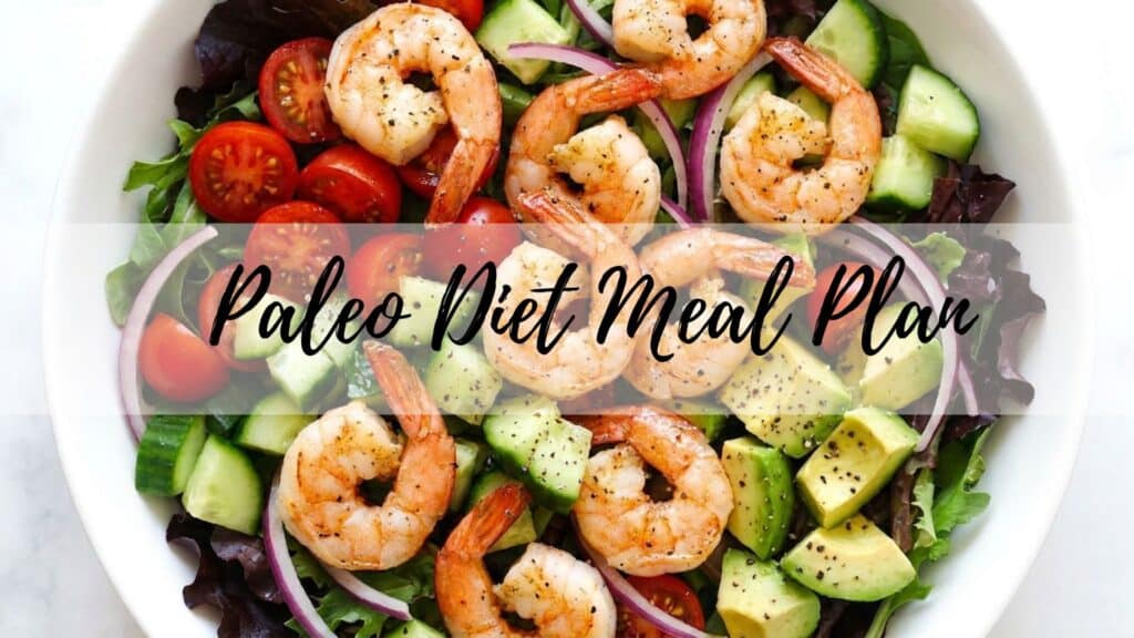 A paleo salad bowl with grilled shrimp, avocado, tomatoes, and greens. Overlay text reads: Paleo Diet Meal Plan.