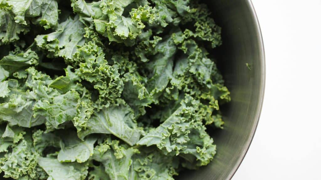 Fresh curly kale leaves in a bowl highlighting kale benefits for heart health, digestion, immunity, and healthy nutrition.