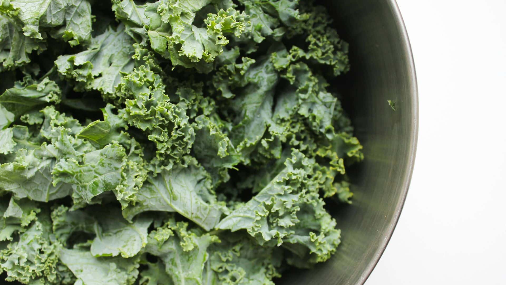 Fresh curly kale leaves in a bowl highlighting kale benefits for heart health, digestion, immunity, and healthy nutrition.