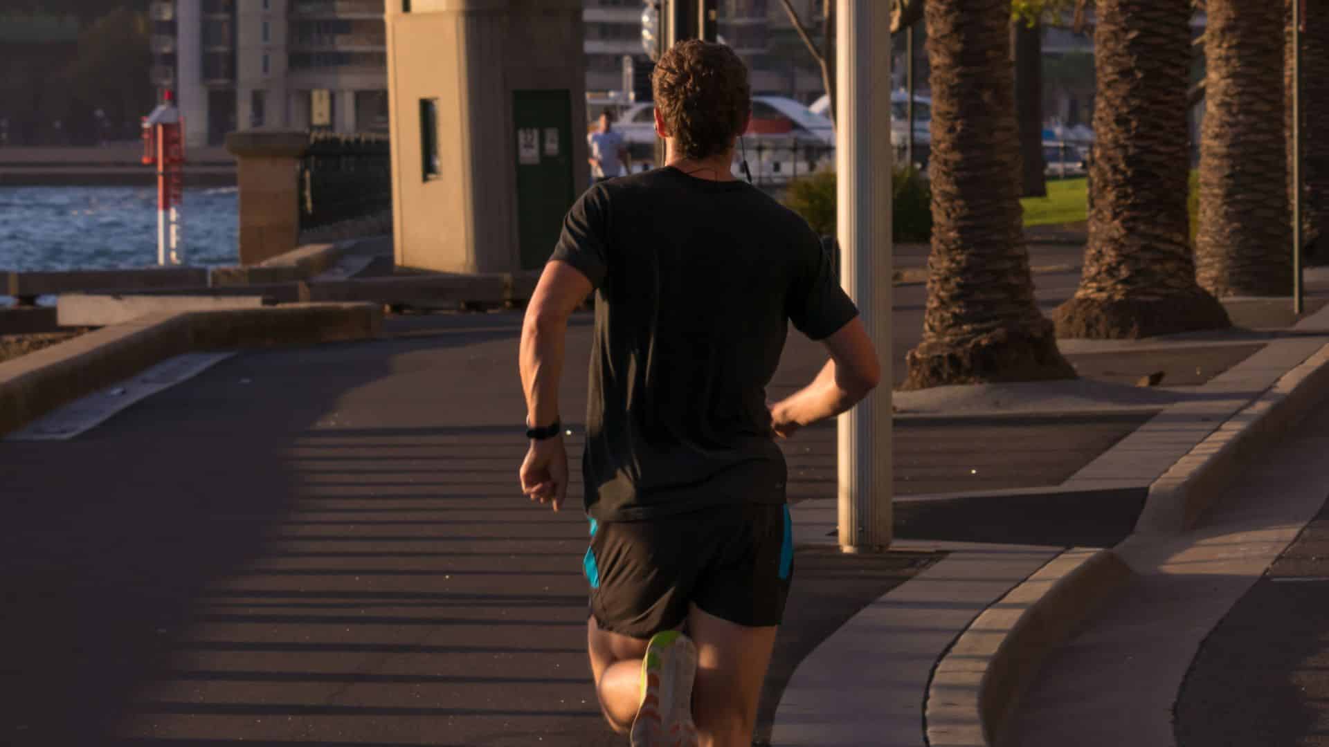 Man jogging along a waterfront path at sunrise, showing how to start running for beginners with a steady outdoor routine.