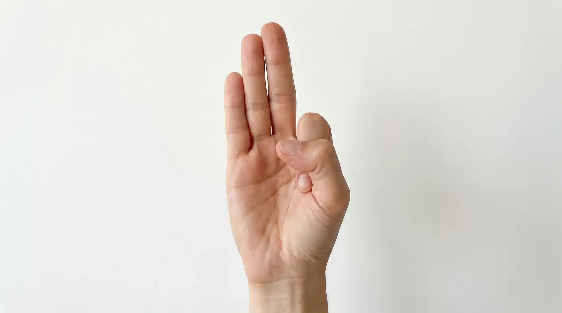 Close-up of a hand in Vayu Mudra, with the index finger folded to the base of the thumb and the thumb pressing over it.