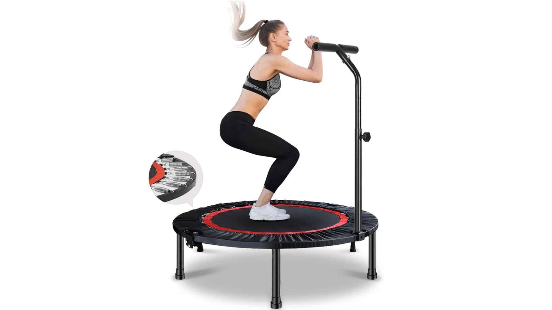 A woman in black sportswear squatting mid-bounce on a black and red VOLKWELL mini trampoline with a stability handlebar.