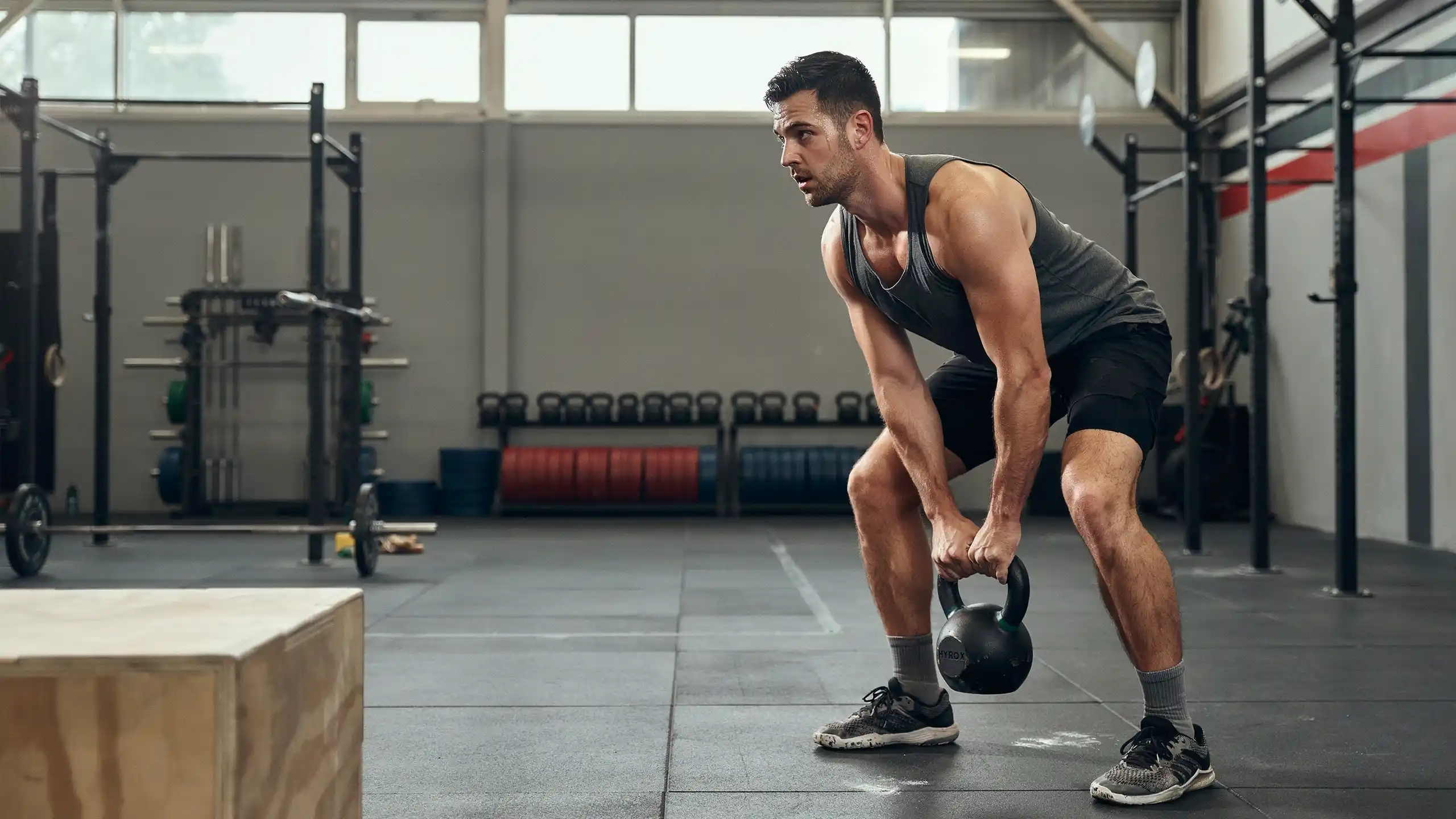 Male athlete performing kettlebell carries during HYROX training, showing functional strength and endurance exercises combined in one workout.