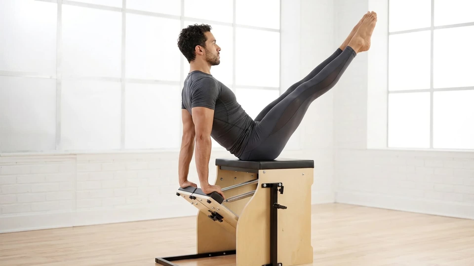 Man performing a Teaser pose on a Pilates Wunda Chair during a STOTT Pilates exercise session.