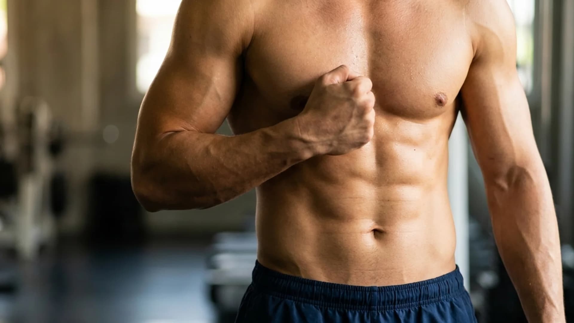 Fit man displaying a naturally developed muscular chest in a modern gym.