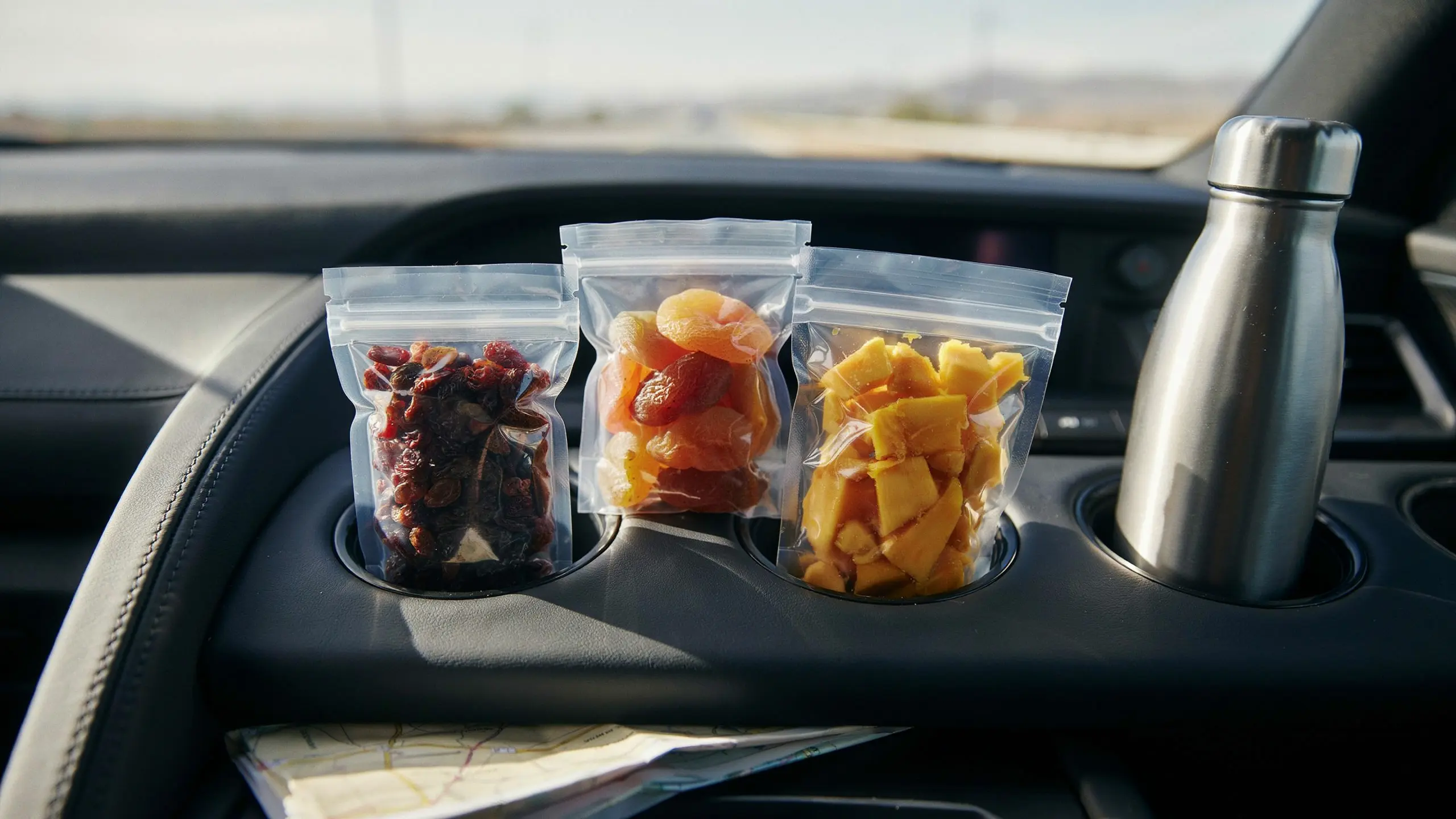 Portioned dried fruits like raisins and apricots packed for a road trip snack.