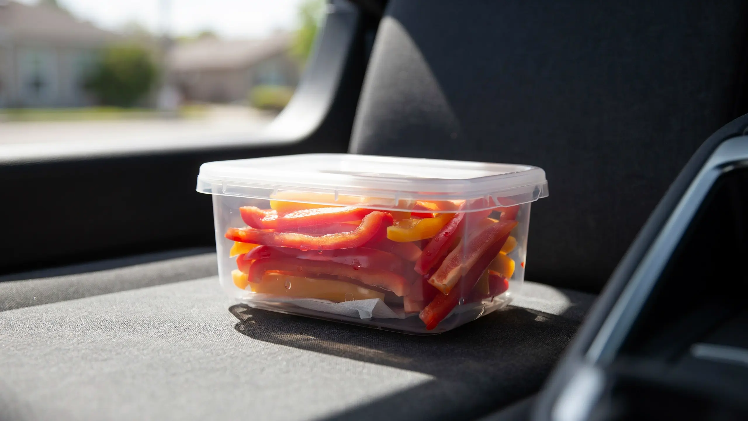 Red and yellow bell pepper strips stored in a container for a road trip snack.