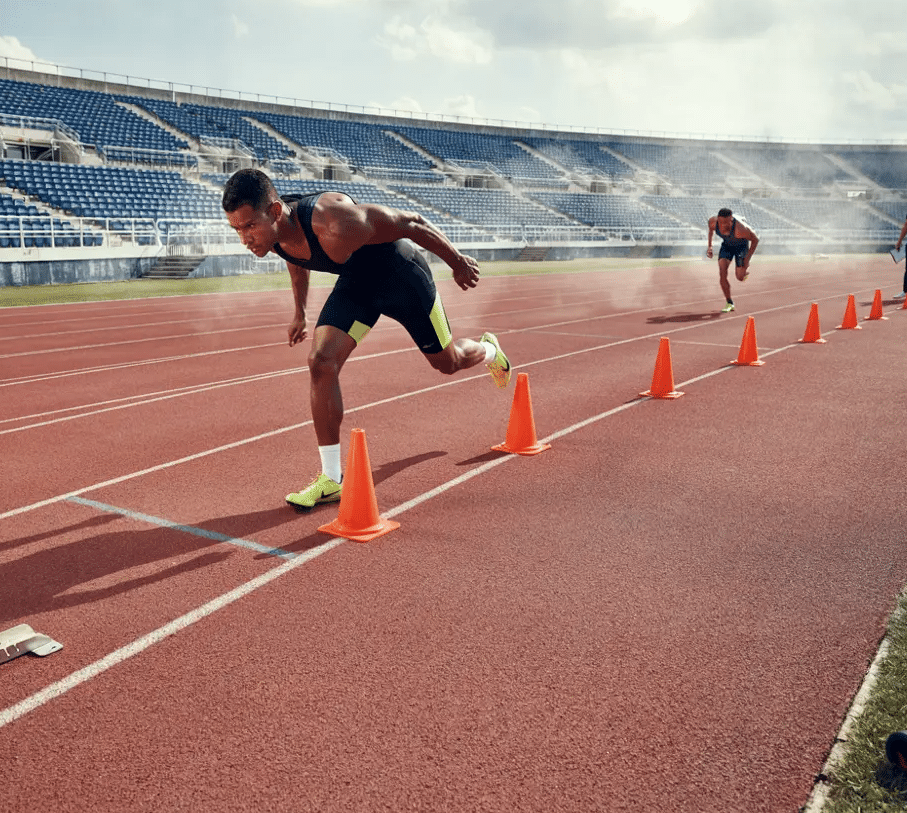 Sprinter performing cone drills on a track to improve acceleration, speed, and running mechanics.