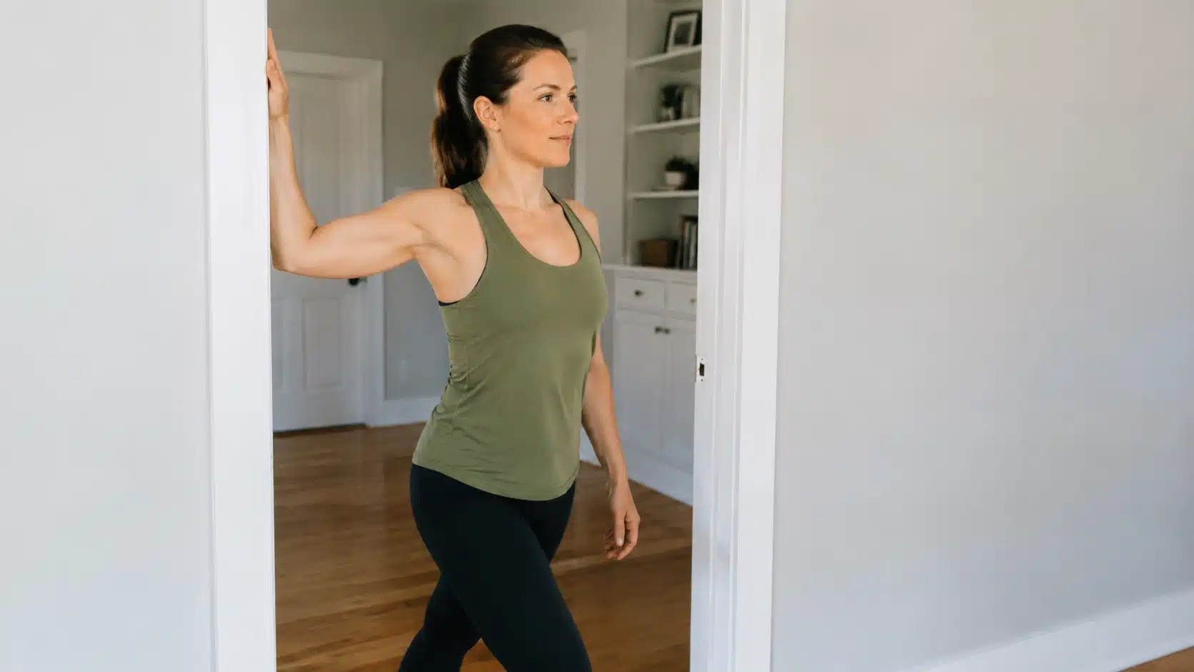 Woman performing a doorway chest stretch at home to loosen tight chest muscles and improve upper body mobility.
